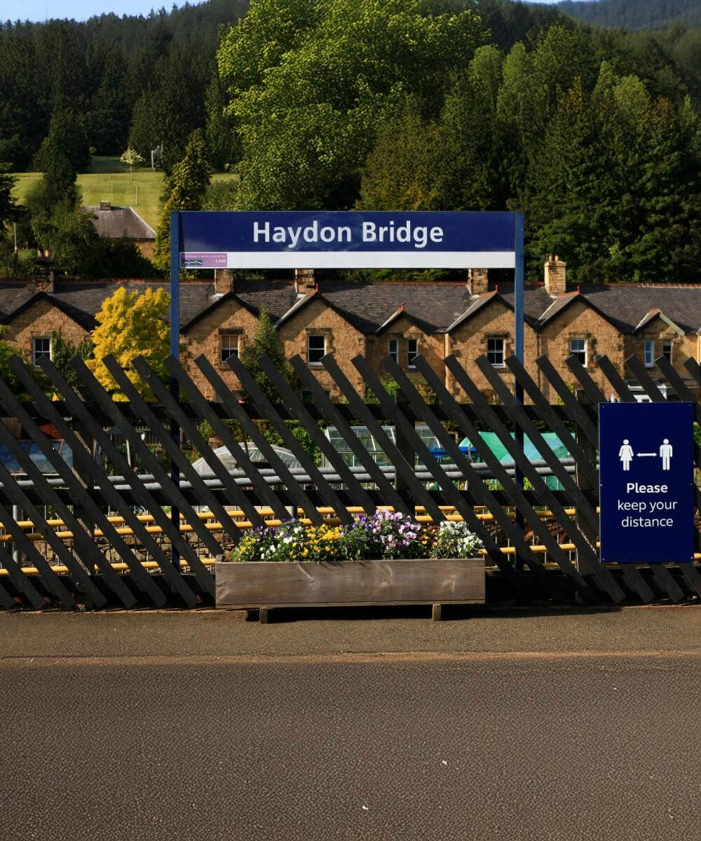 A station platform sign for Haydon Bridge