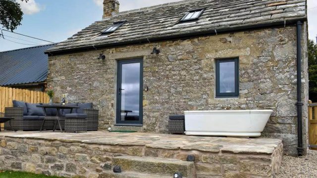 Small cottage with outdoor furniture and bathtub